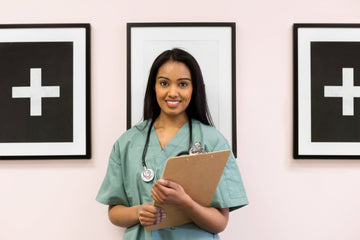 Person in green scrubs holding a clipboard and wearing a stethoscope